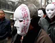 近幾年，由于經濟增速下行，中西部地區和中小城市成為當前討薪矛盾多發地區。一邊是國家和地方維護打工者權益的法律法規不斷出臺，另一邊則是“年年干活年年欠，年年討薪年年難”。不少打工者不得已只好采取行為藝術等手段以博取關注。圖為2015年2月2日，西安市尚德路陜西省水利廳的門前，七八位頭戴著白色面具者站在凜凜寒風中，面具上寫著：“含淚討工錢” “無顏見父母”等標語。據了解，這幾個人是70名農民工的代表，他們之前在武功縣干的工程被欠款156萬元。誰知，包工頭不但電話打不通，以前的家也搬了，根本找不到人，多次找到水