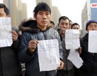 承建商已將工程款給付90%，但包工頭宋林卻把錢拿走不給工人結工資。一氣之下，十多名工人將包工頭車和人扣下，一不留神卻讓包工頭翻墻跑了。2015年12月31日，在勞動監察部門協調下達成初步協議，包工頭將工人手續移交到成泰公司，由成泰公司替宋林代付一半工資，但在移交工人手續的時候包工頭害怕再次被扣卻一直不敢露面。1月3日，包工頭給農民工發來短信，并要求寫下承諾書，保證不扣他本人。圖為1月5日，陜西商洛，討薪農民工在工地上出示欠條和他們寫給包工頭的承諾書。華商報記者 閆文青/視覺中國