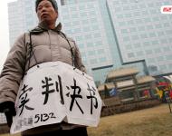 2006年1月24日，在京從事降水井工程的老陳掛著寫有“賣判決書”的紙口袋在北京站口附近來回走著。曾是名小工頭的老陳被欠工程款4萬元，為了給工人們開資不得已賣掉了打井機器。2002年法院宣判老陳勝訴，可四年后該判決仍得不到執行，無奈之中老陳只好上演此幕。程寧/視覺中國